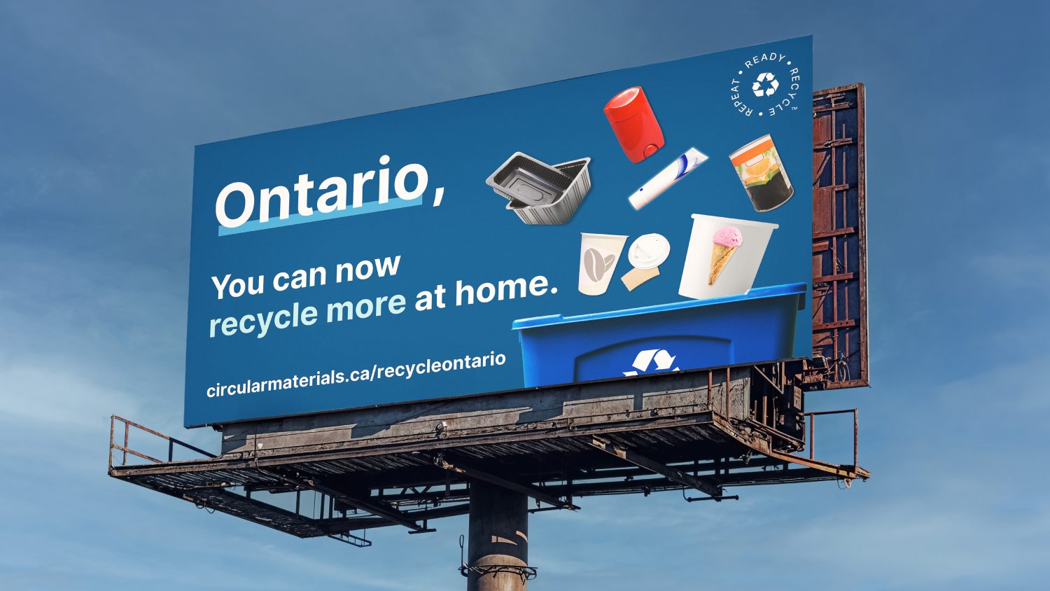 Billboard displaying a recycling visual, with text "Ontario, you can now recycle more at home".